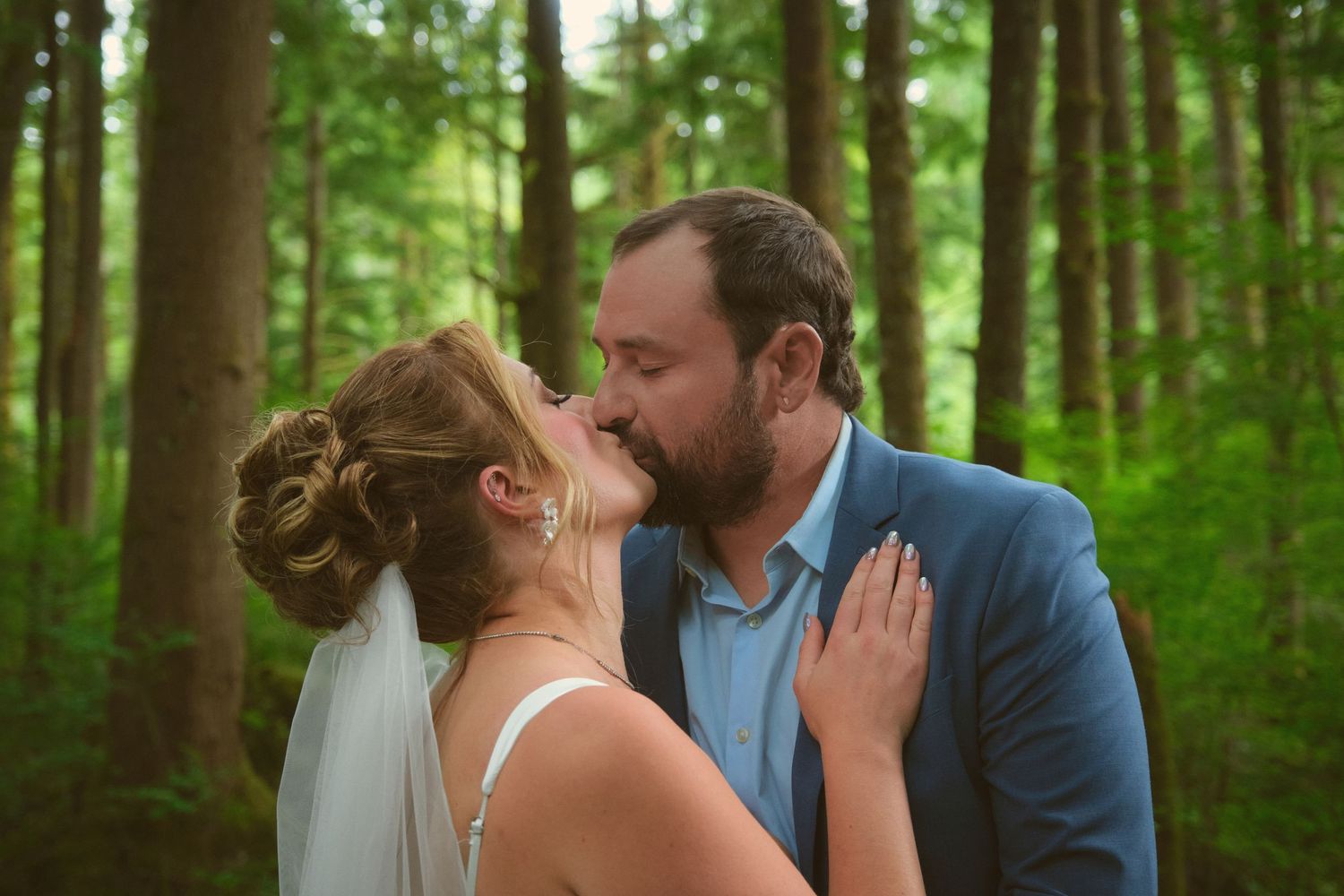 A photo of a married couple sharing a kiss in a Washington State forest. Photo by N&D Wedding Photography and Film