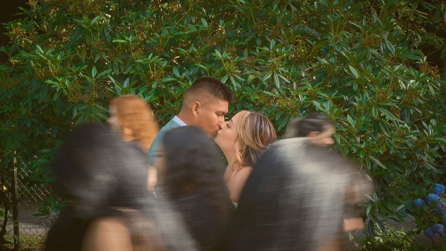 Newlyweds kissing as people pass by outside in Tulalip Washington. Photo by N&D Wedding Photography and Film