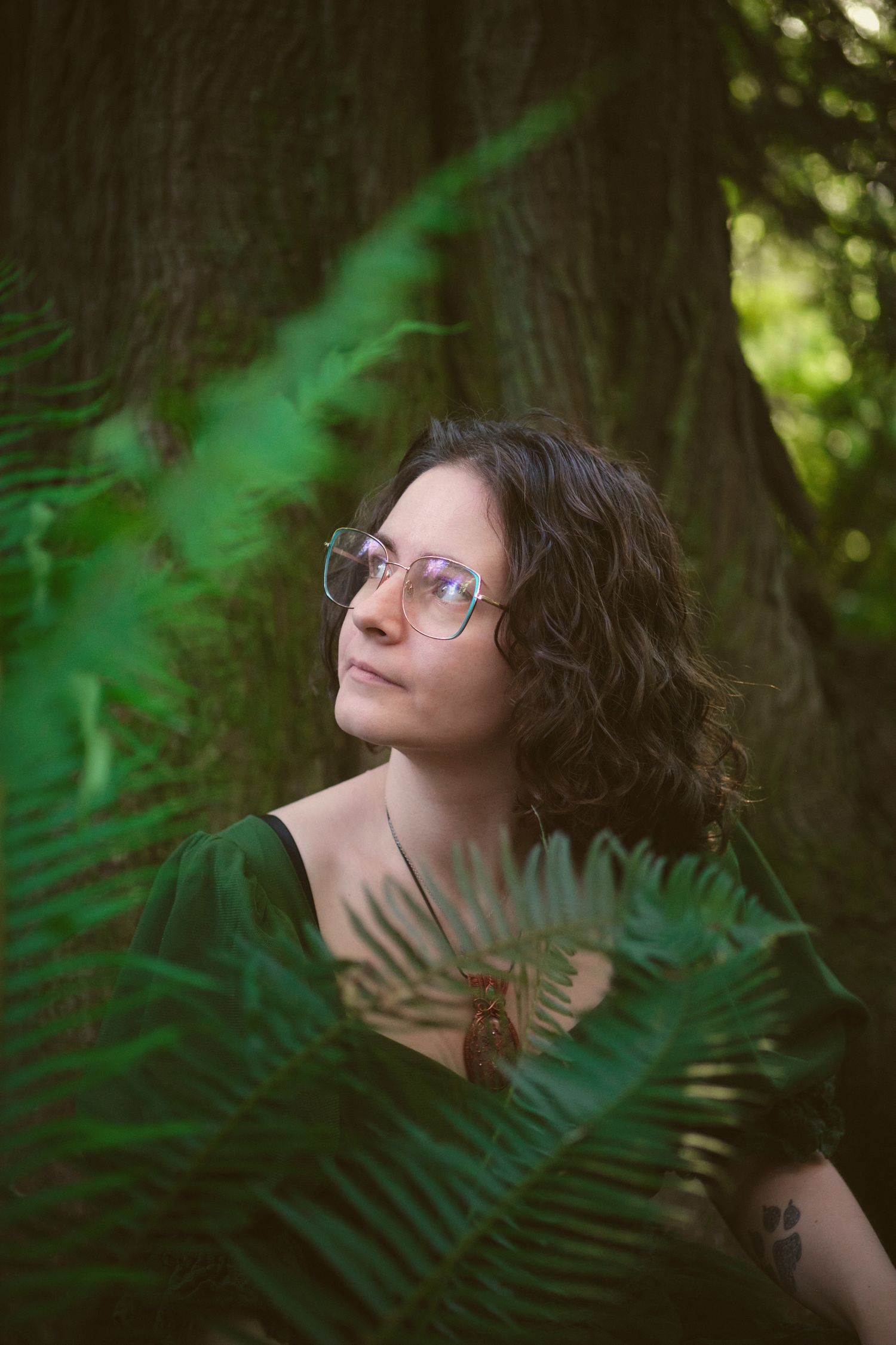 A photo of Foggé Crystal Company owner Miranda sitting in some ferns in a Washington State forest. Photo by N&D Wedding Photography and Film