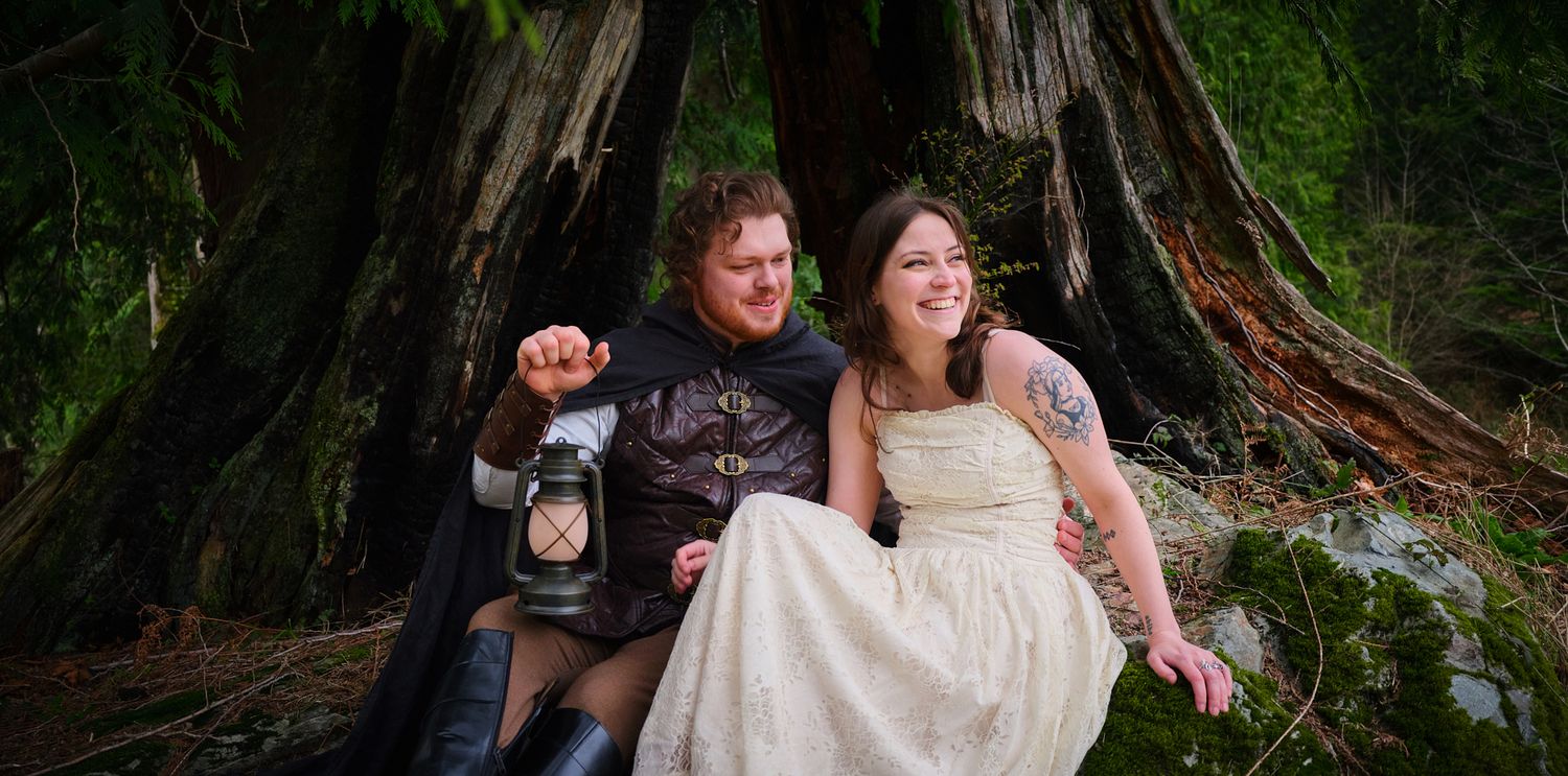 A couple sitting near a hollowed out tree, one of them is smiling and laughing taken in WA, State. Photo by N&D Wedding Photography and Film