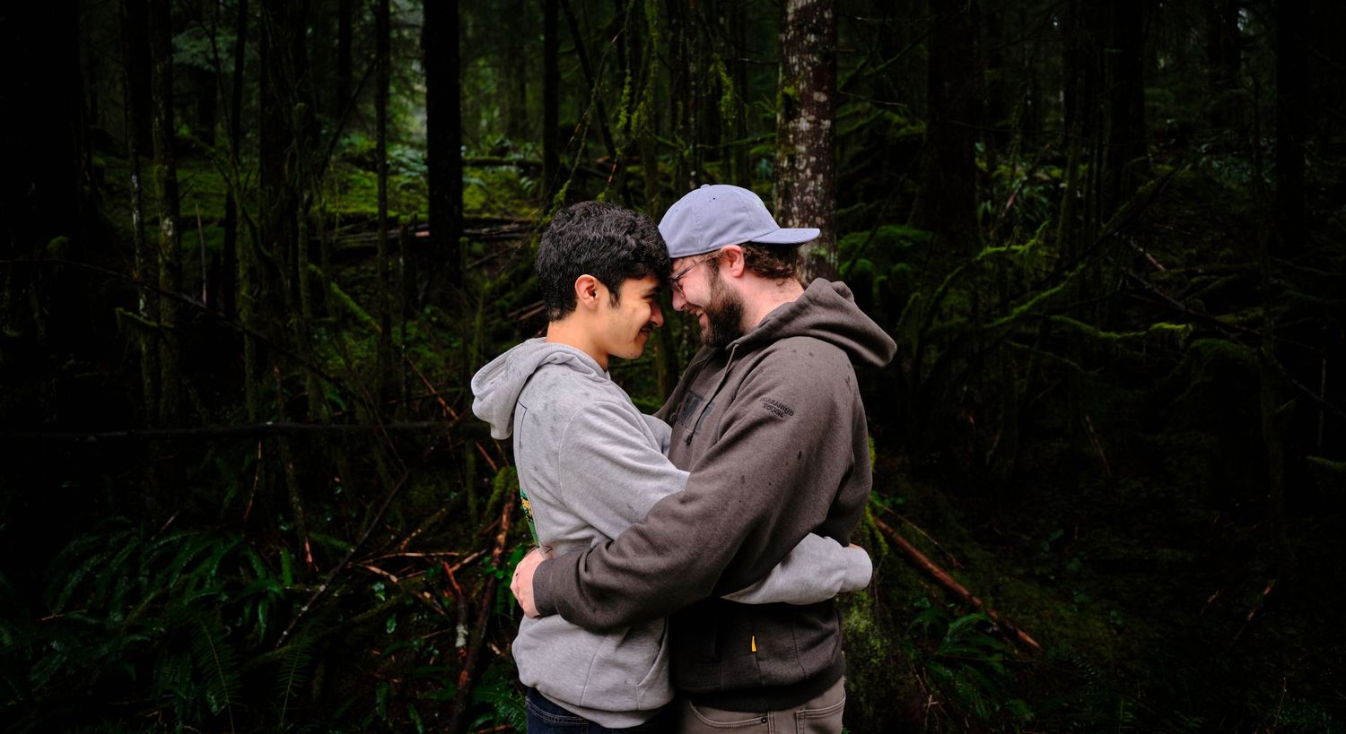 A couple embracing and touching their heads together in a Washington State forest in the rain. Photo by N&D Wedding Photography and Film
