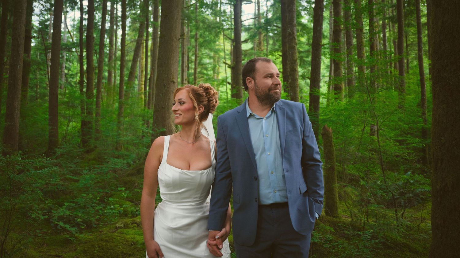 A photo of a married couple holding hands and smiling while standing in a Washington State forest. Photo by N&D Wedding Photography and Film