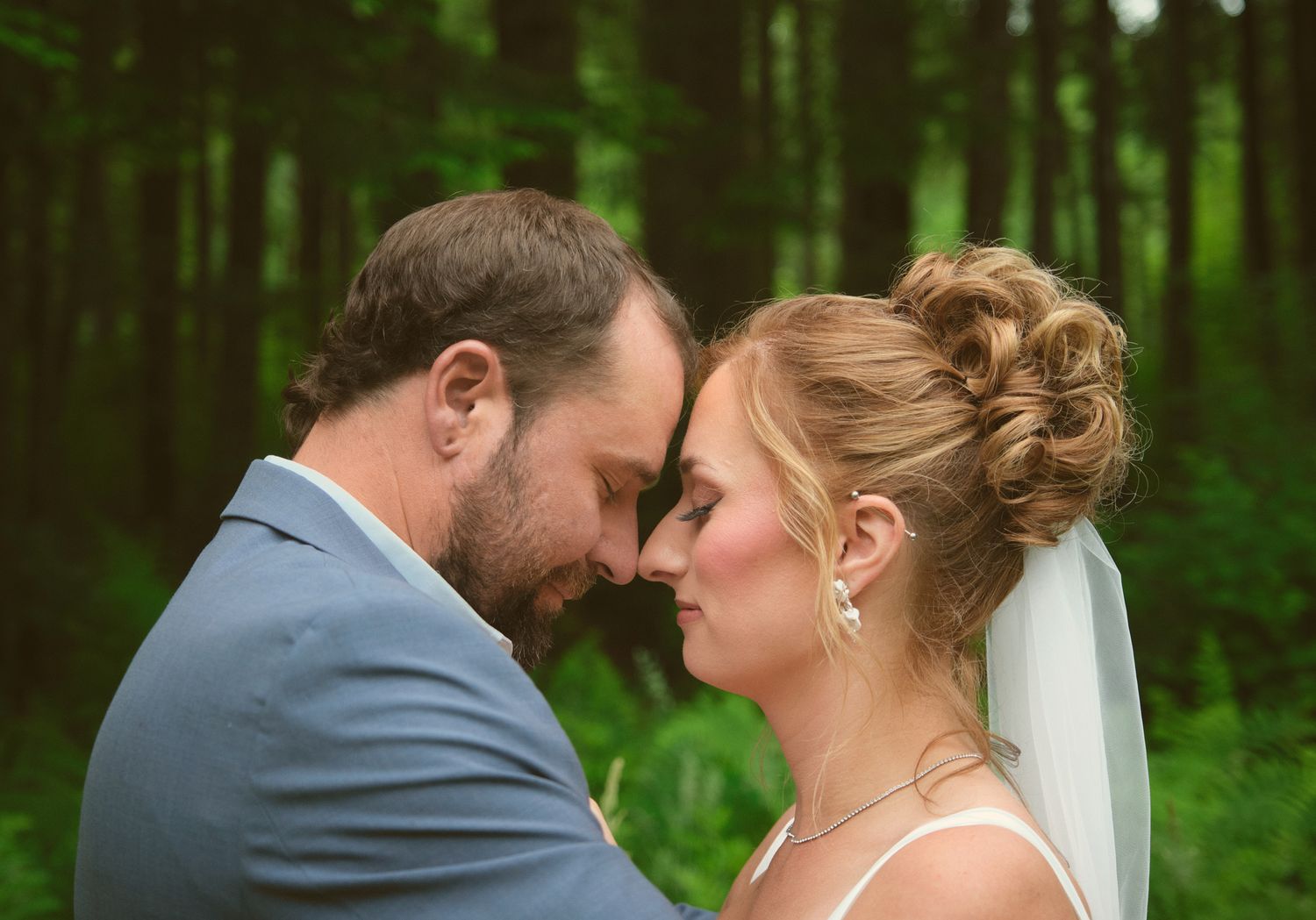 A photo of a married couple leaning their heads close together in a Washington State forest. Photo by N&D Wedding Photography and Film