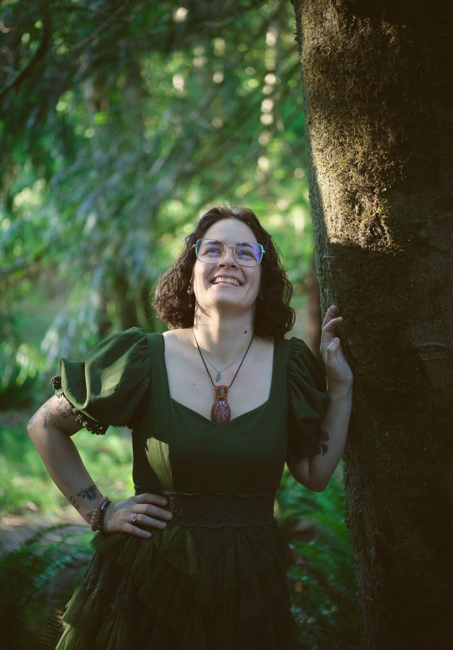 A photo of Foggé Crystal Company owner Miranda leaning on a tree in a Washington State forest. Photo by N&D Wedding Photography and Film