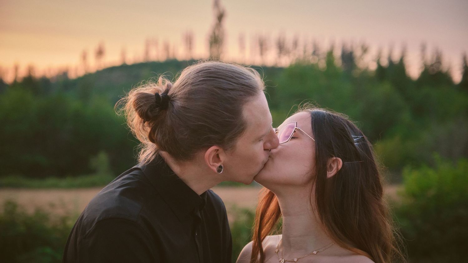 An engaged couple kissing in front of a field in Snohomish County. Photo by N&D Wedding Photography and Film