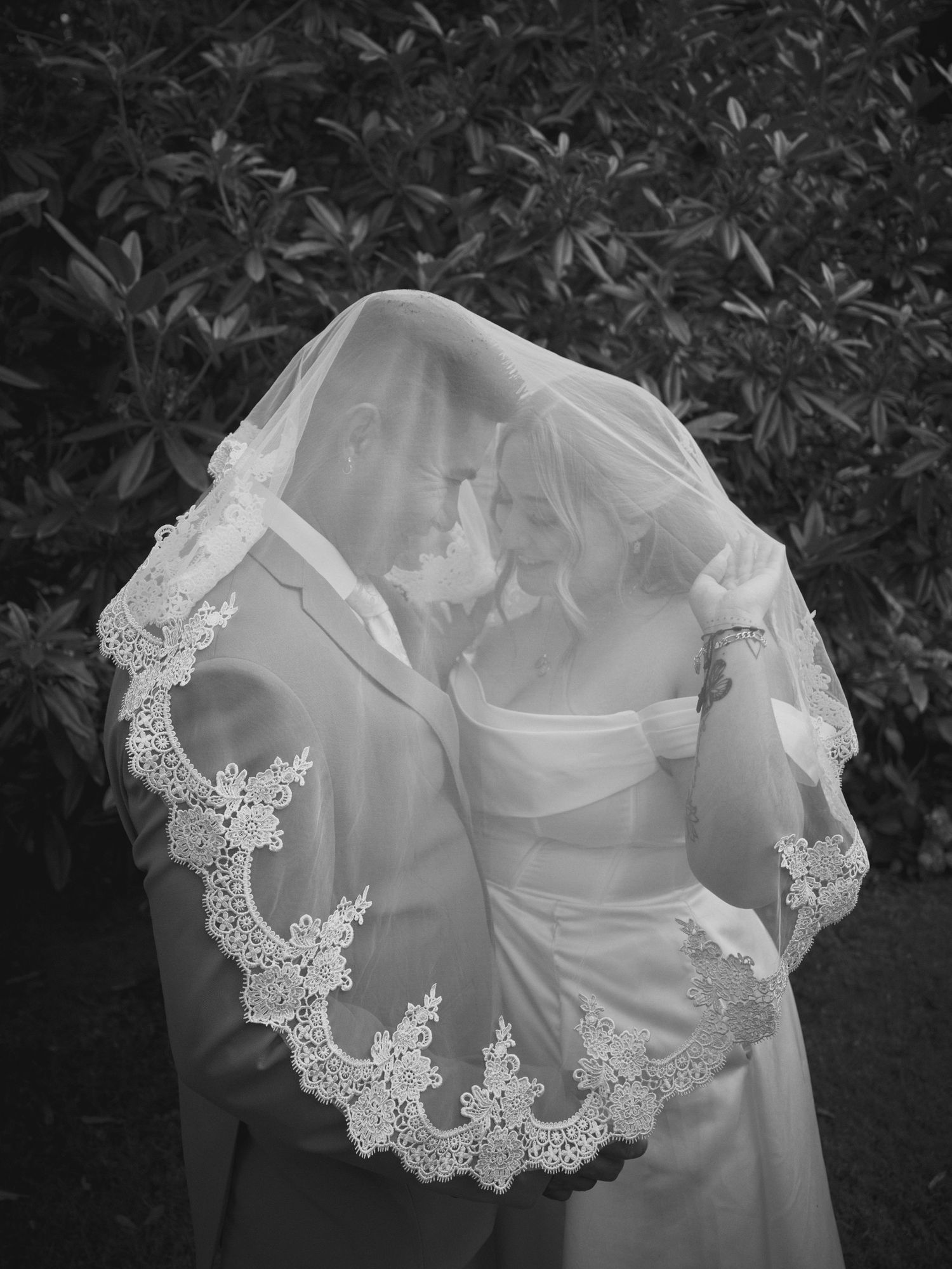 A bride and groom being playful under the bride's veil outside in Tulalip Washington. Photo by N&D Wedding Photography and Film