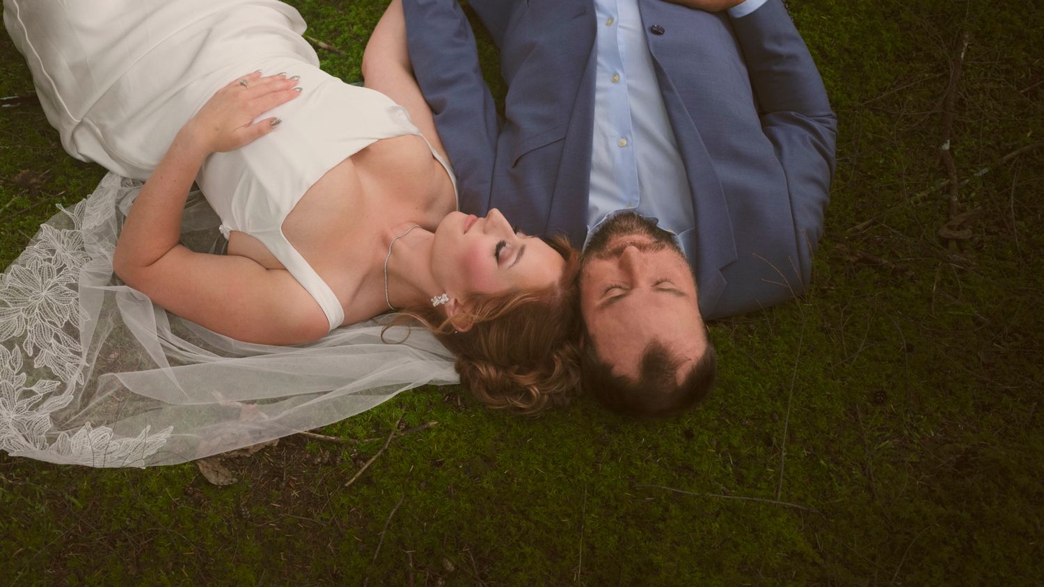 A married couple in a WA State forest on the ground with their eyes closed and heads touching. Photo by N&D Wedding Photography and Film