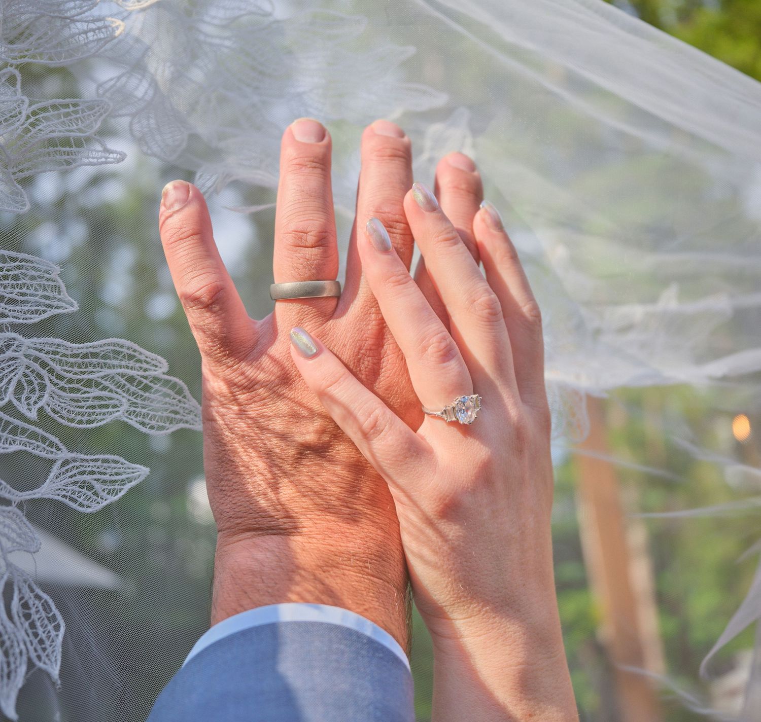 A photo of two newlyweds ring fingers, they are holding them in the air in Washington State. Photo by N&D Wedding Photography and Film