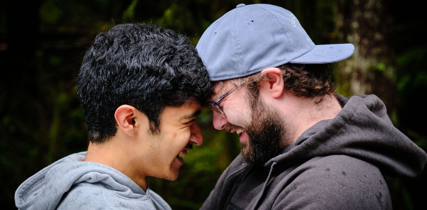 A couple touching their heads together in a cute way in a Washington State forest in the rain. Photo by N&D Wedding Photography and Film