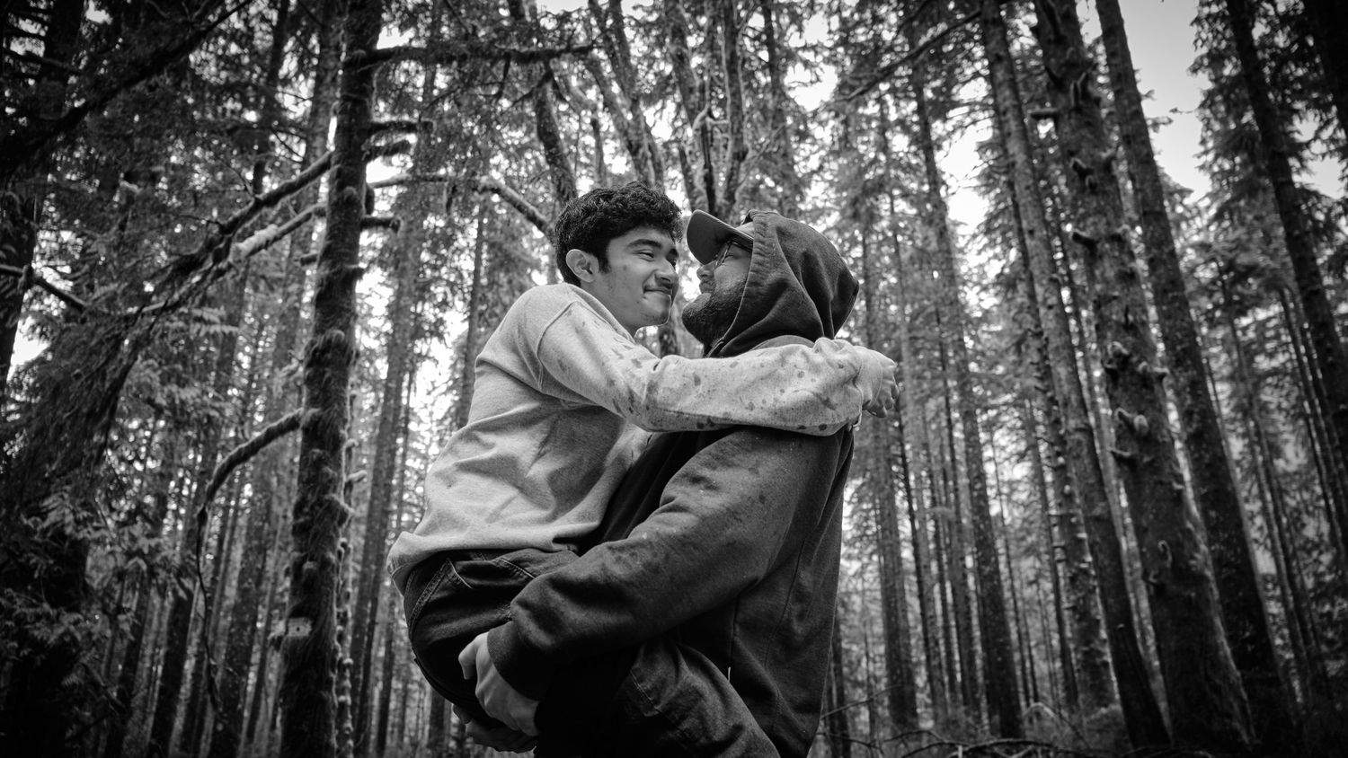 A couple holding each other in a WA, State forest in the rain, one of them is carrying the other. Photo by N&D Wedding Photography and Film