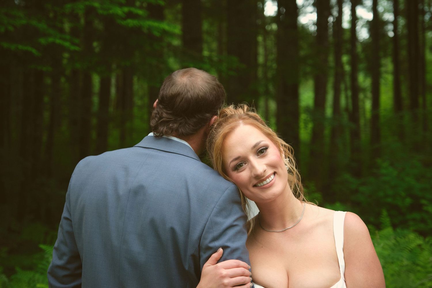 A photo of a bride wrapping her arm around her husband's as he faces the other direction. Photo by N&D Wedding Photography and Film