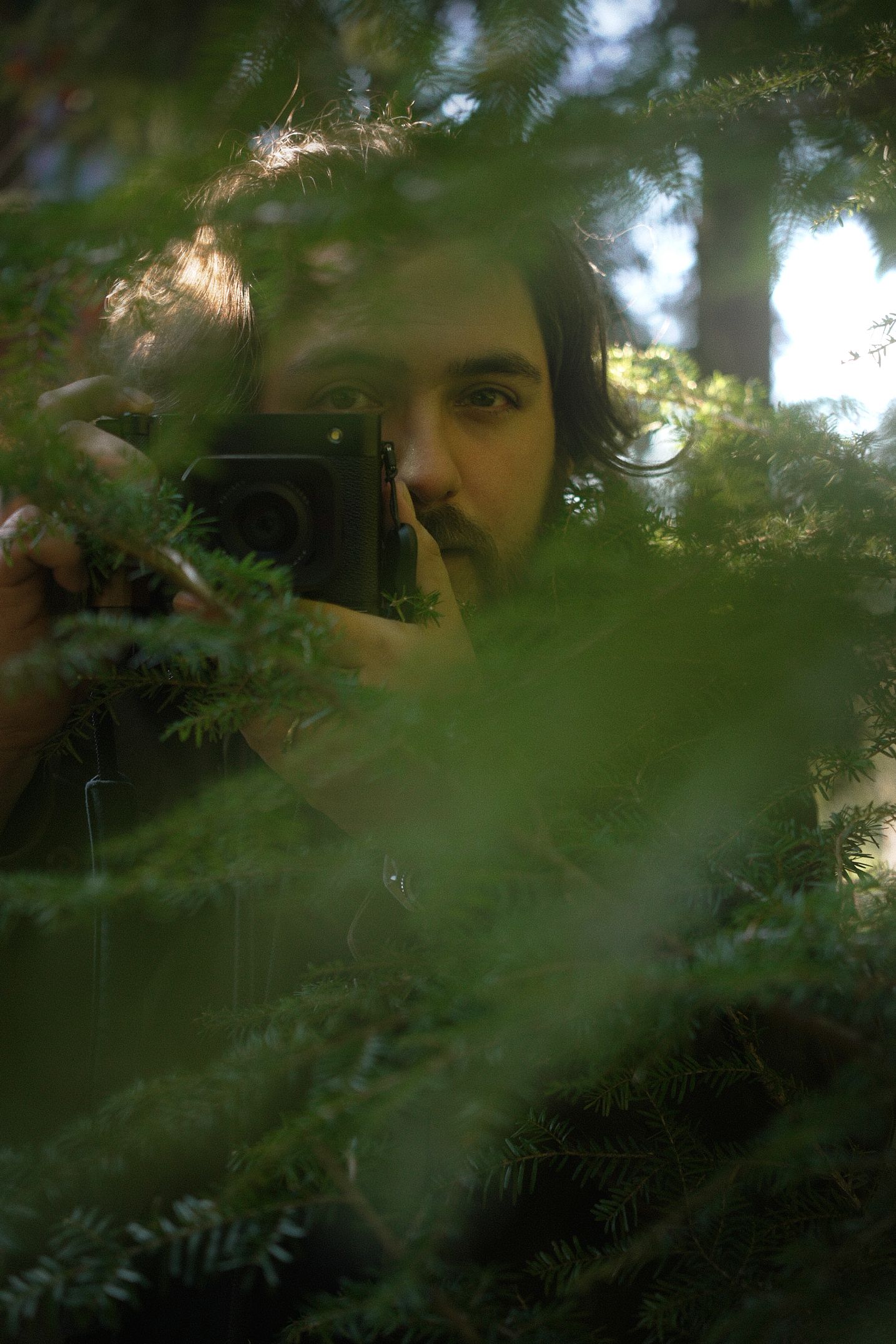 Dawson the photographer for N&D Wedding Photography and Film taking a picture with his GFX 100RF in a forest in Washington State.