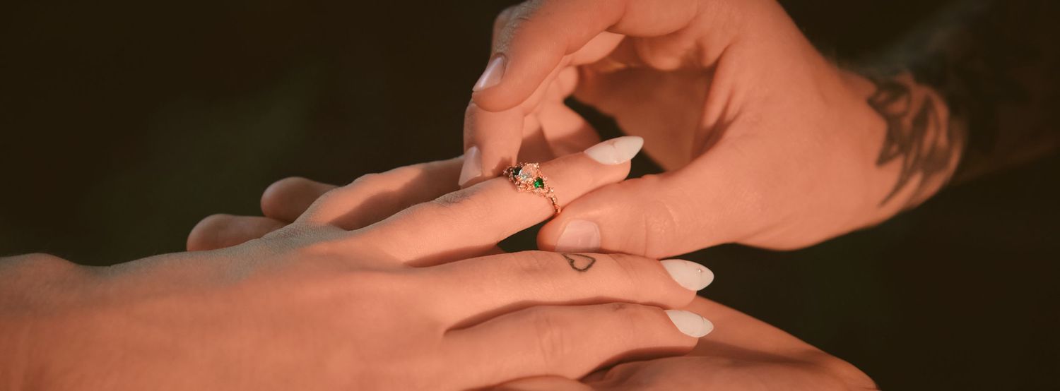 A fiancé placing a ring on their partner's finger in a forest in Washington State. Photo by N&D Wedding Photography and Film