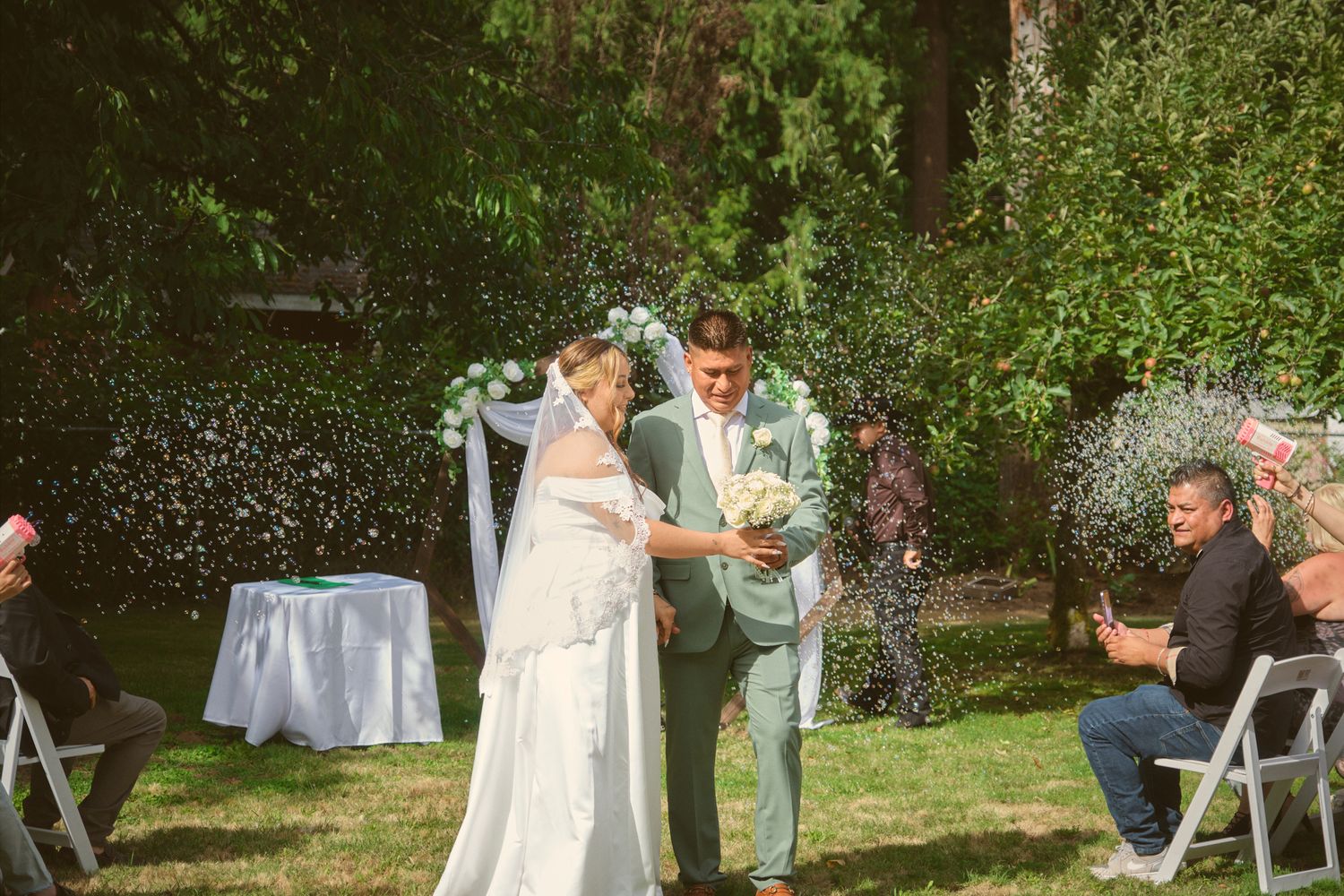 The groom handing his bride the bouquet as they are walking down the aisle in Tulalip Washington. Photo by N&D Wedding Photography and Film