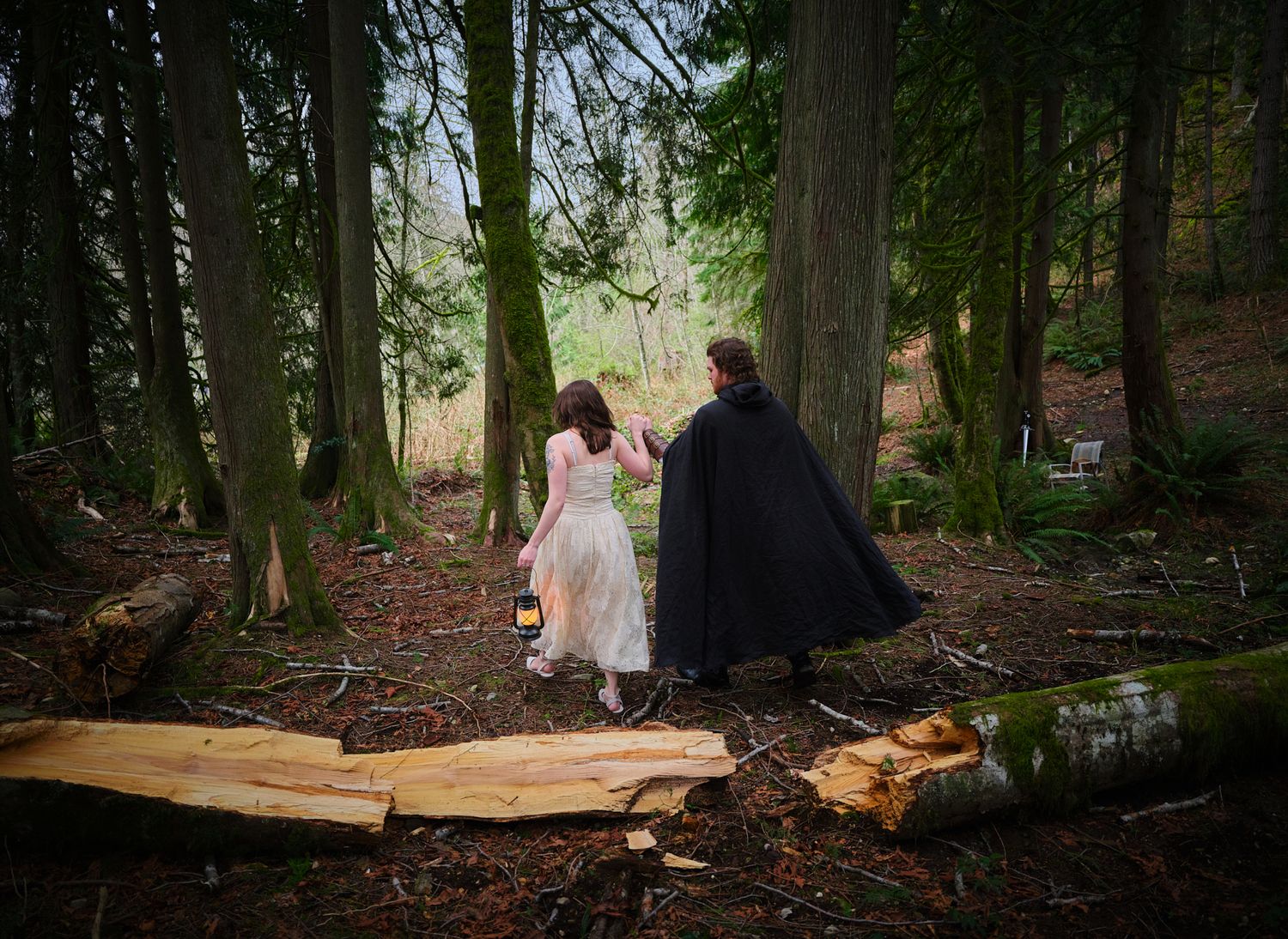 A couple walking through the woods in Washington State while holding a lantern to light the way. Photo by N&D Wedding Photography and Film