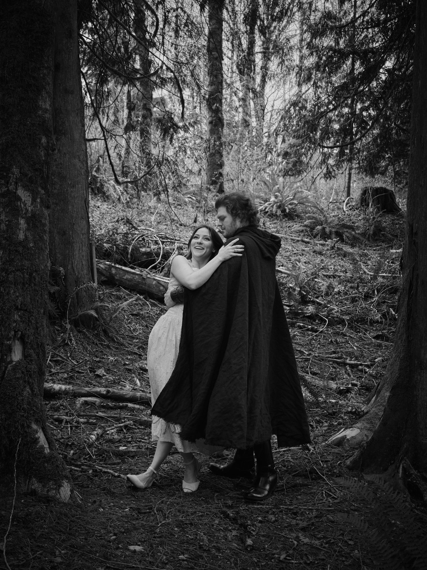 A couple laughing as one of them falls and the other catches them in a Washington State forest. Photo by N&D Wedding Photography and Film