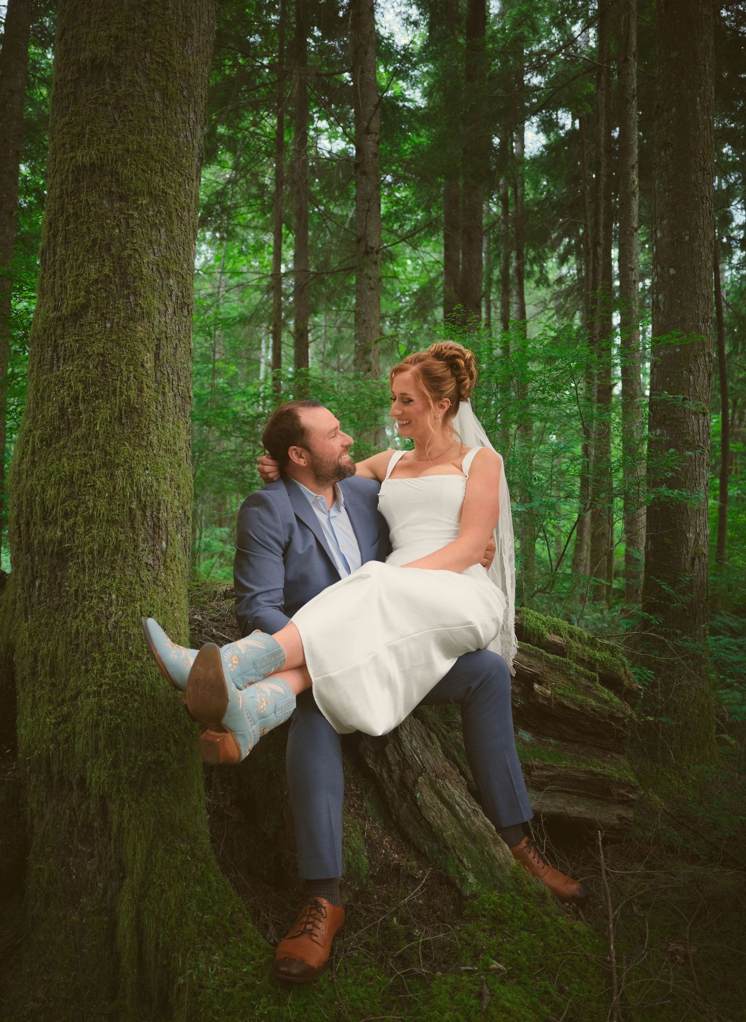 A photo in the WA State woods of a newly married couple, the bride is sitting in the groom's lap . Photo by N&D Wedding Photography and Film