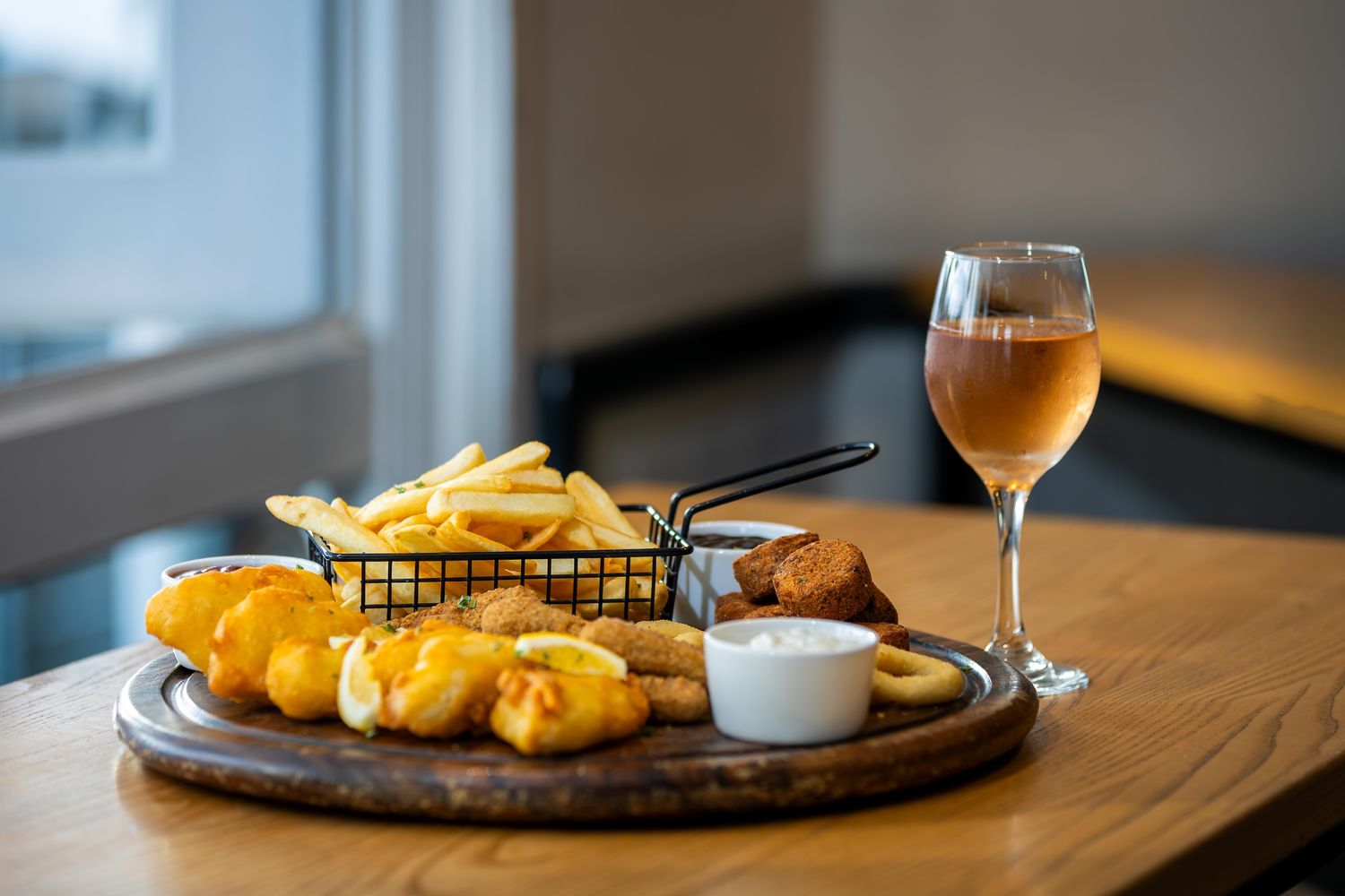 Beer battered fish and chips served with dipping sauce in a modern restaurant setting.