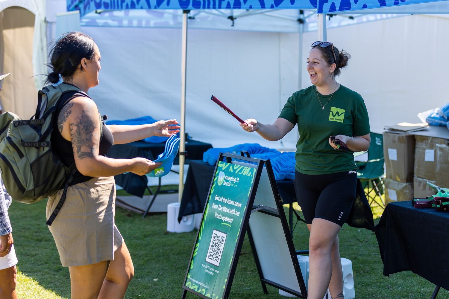 Event staff managing promotional materials at outdoor tables and displays.