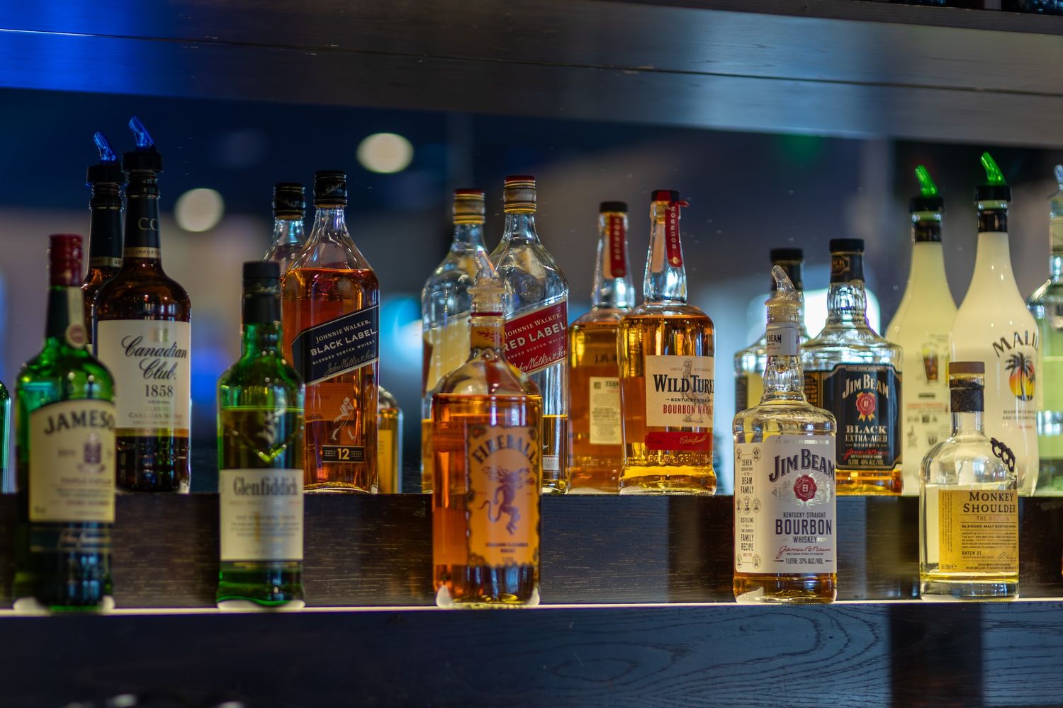 Backlit display of premium spirits and liquor bottles arranged on bar shelving.