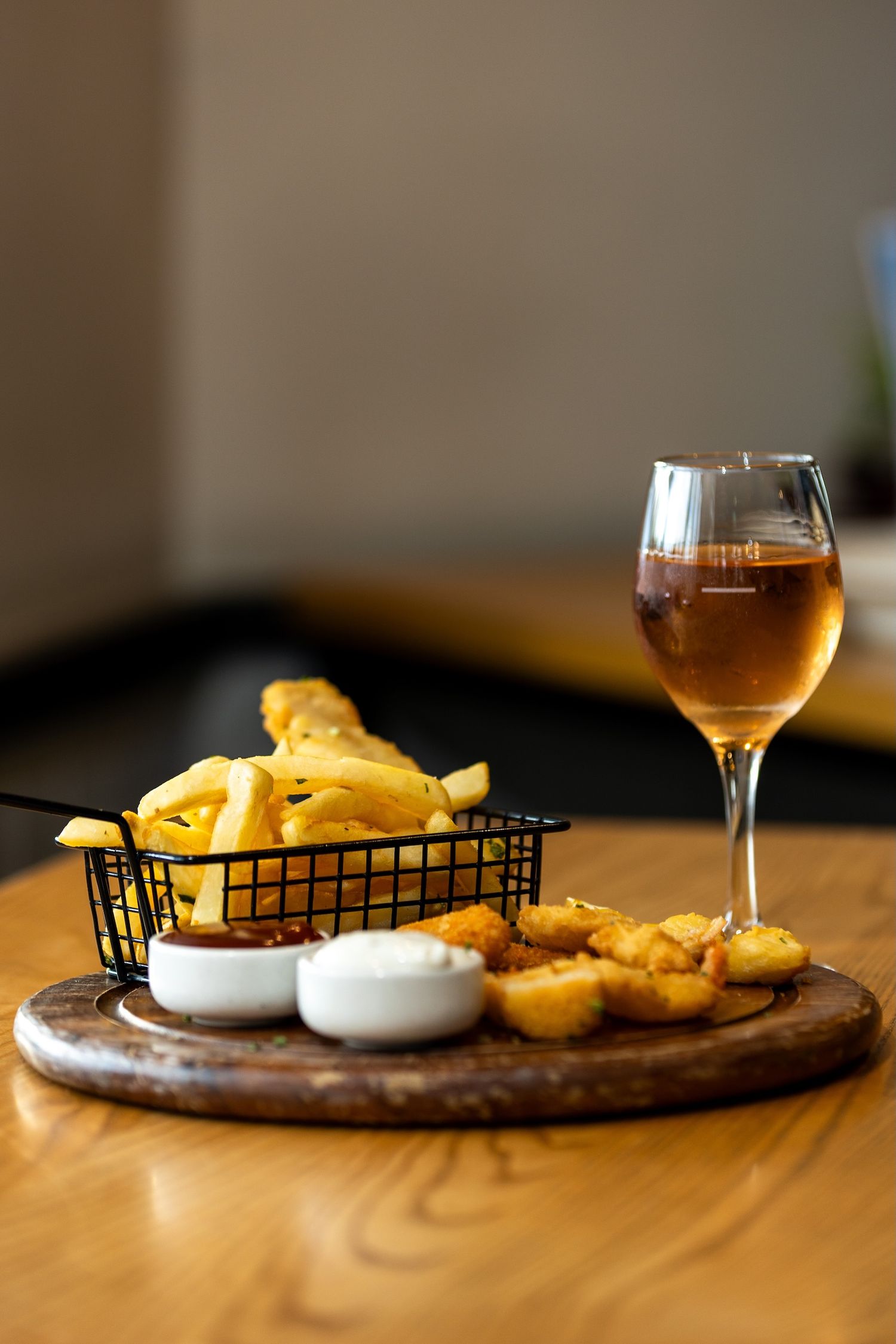 Gastropub style fish and chips with dipping sauces on a rustic wooden serving board.