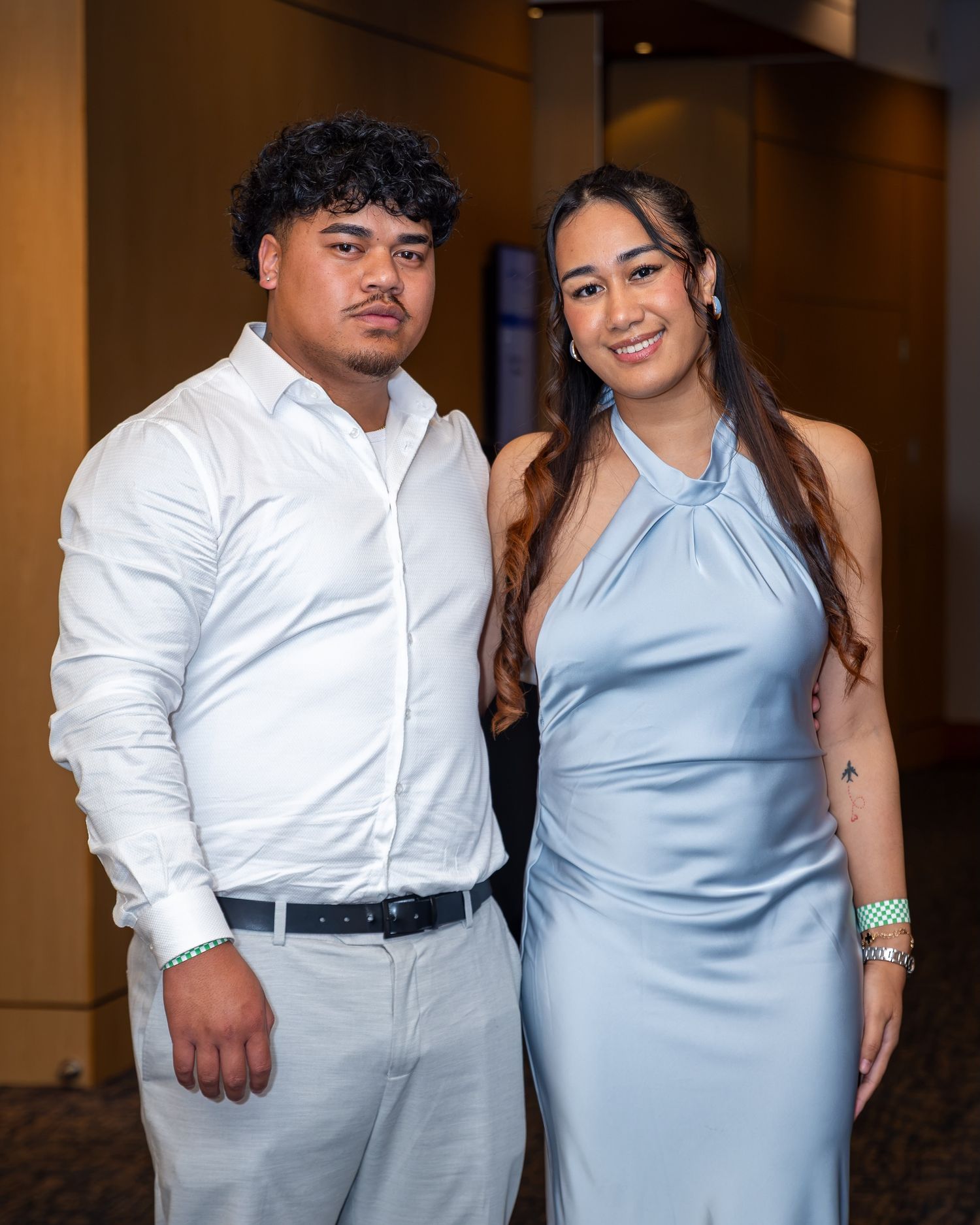 A young couple poses together at a formal event, wearing light blue and white dress attire.