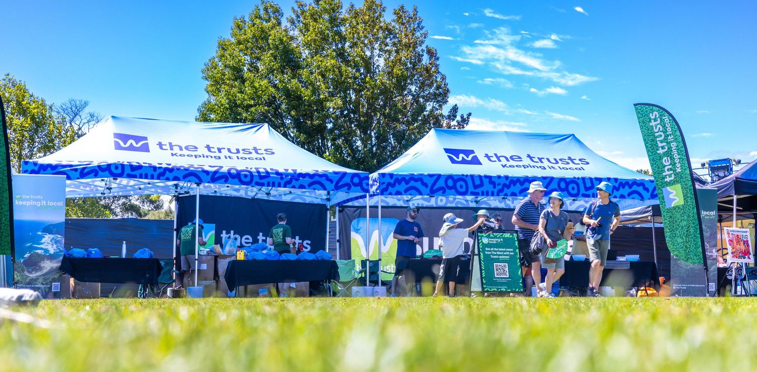 Row of blue and white promotional tents with attendees at an outdoor festival.