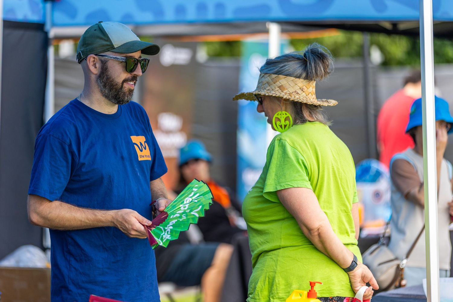 Festival participants in casual attire exchanging items at outdoor community event.