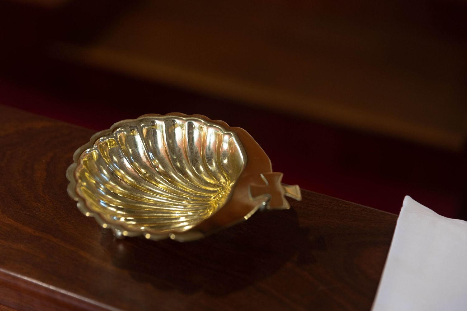 Gold shell-shaped dish on a wooden surface, elegant decorative brass bowl with scalloped edges.