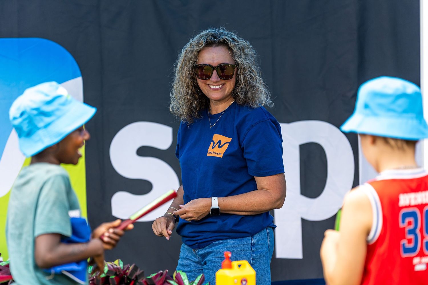 Staff members wearing sunglasses and branded t-shirts at an outdoor event setup.