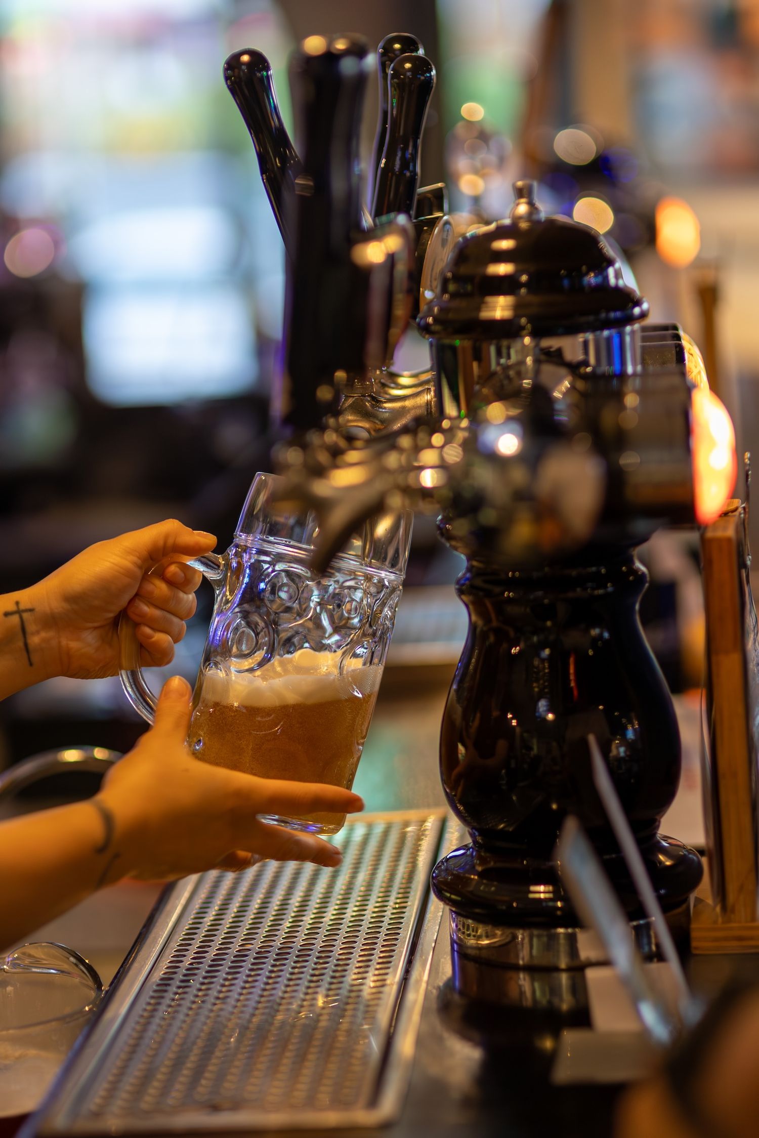 Beer tap system and drip tray at bar counter with glasses being served.