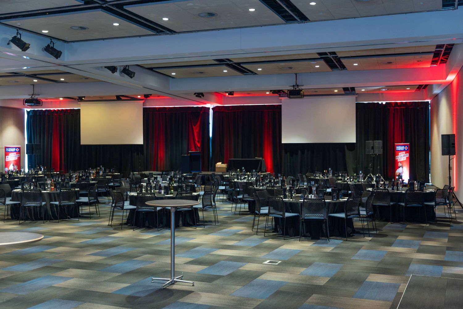 Large event space with checkerboard carpet and red accent lighting for an awards ceremony.