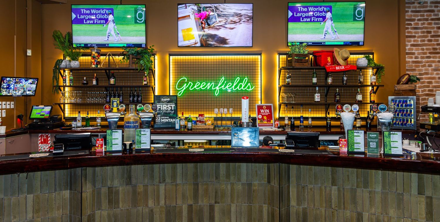 Interior view of a restaurant or bar with digital menu displays and brick walls visible.