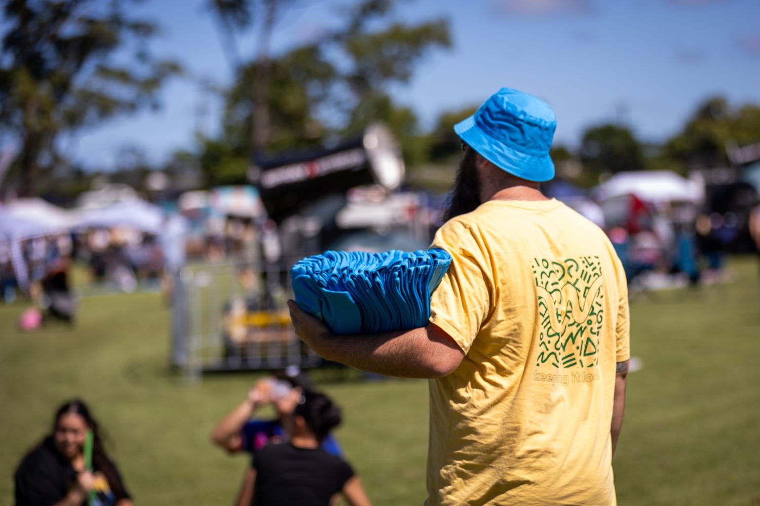Event attendees in yellow and blue shirts walking through outdoor festival area.