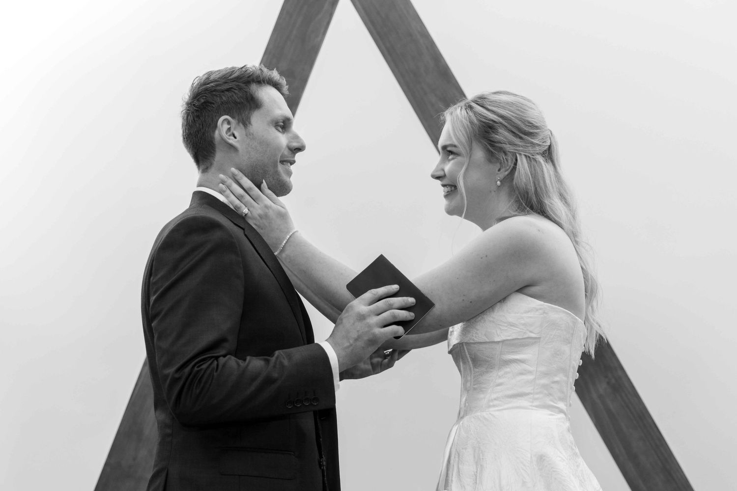 A joyful wedding couple shares a candid moment together in black and white.