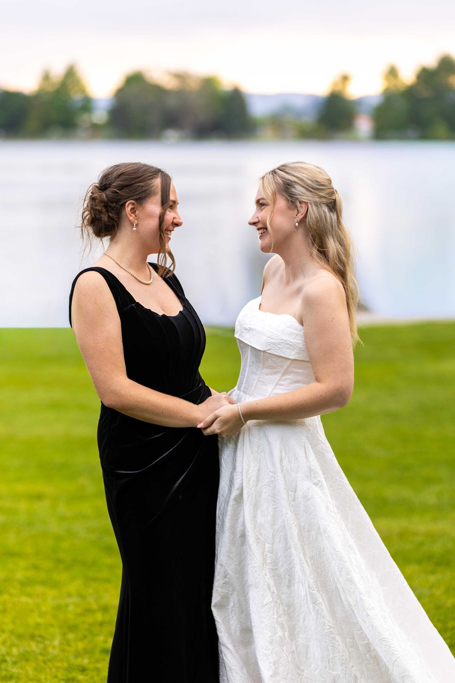 Two people share a happy moment together on a lakeside lawn.