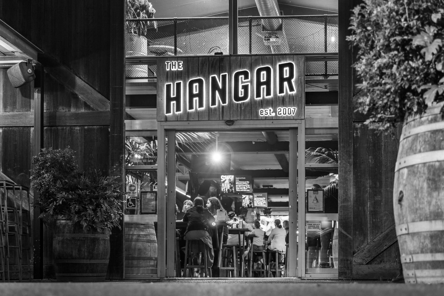 A black and white panoramic collage of vintage storefronts and street scenes showing historic downtown buildings.