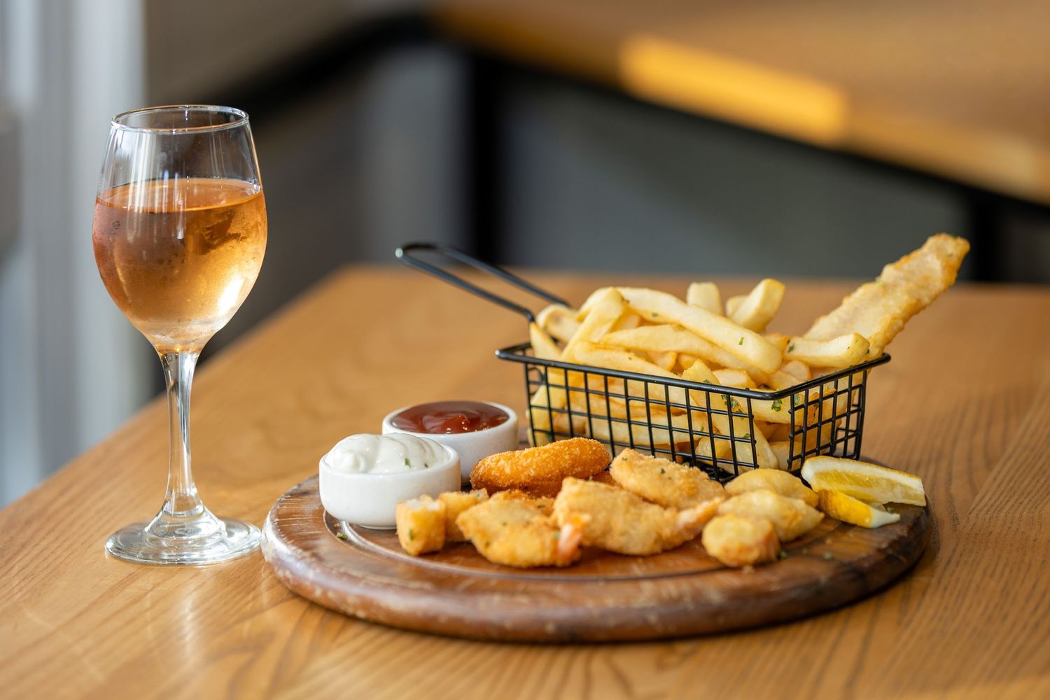 Fish and chips platter with golden beer and condiments on a wooden table.