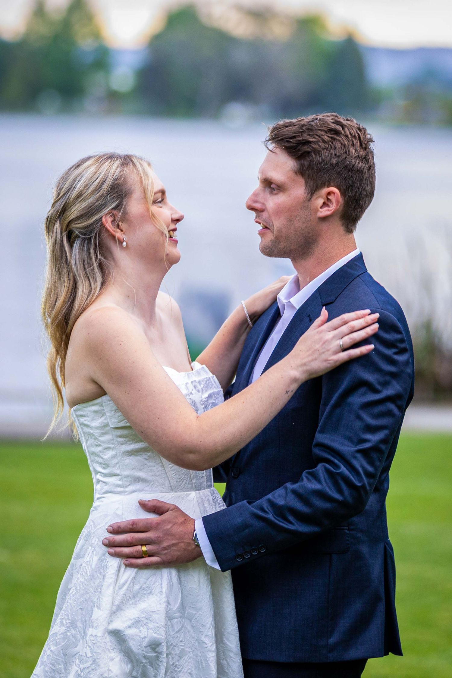 Romantic couple sharing intimate moments on a grassy lawn by the water.