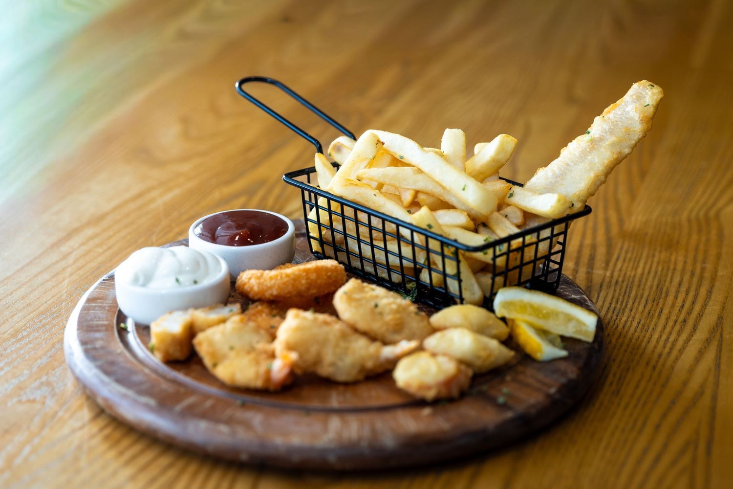 Casual dining spread with french fries, onion rings and dipping sauces in wire baskets.