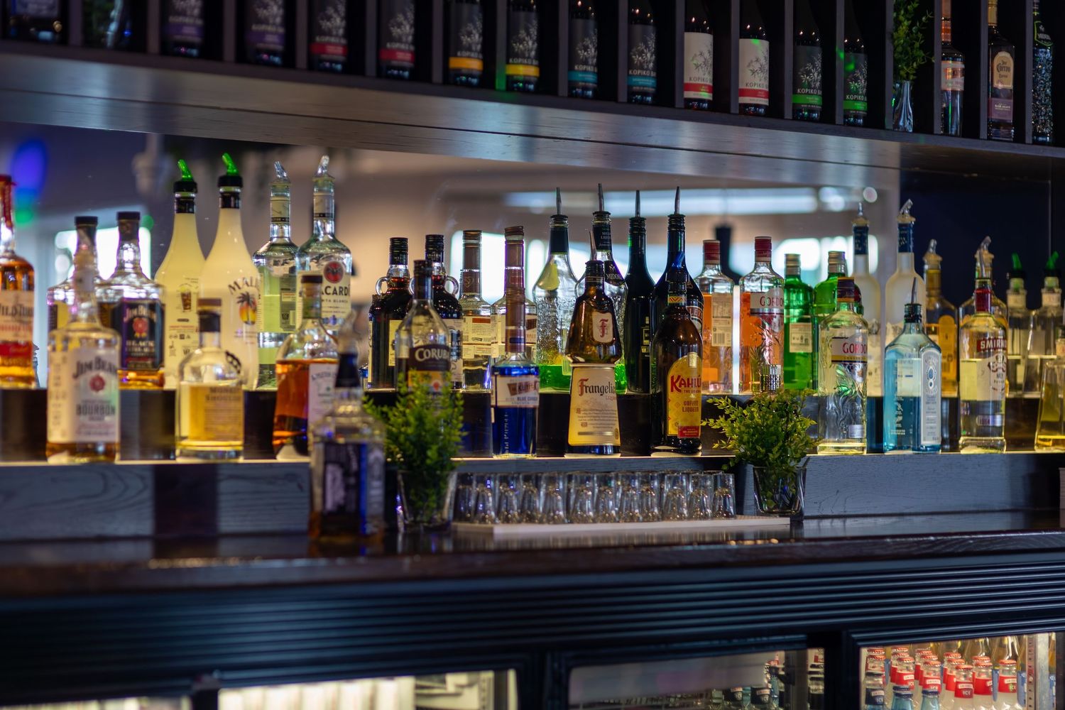Professional bar setup with extensive selection of spirits displayed on illuminated shelving.