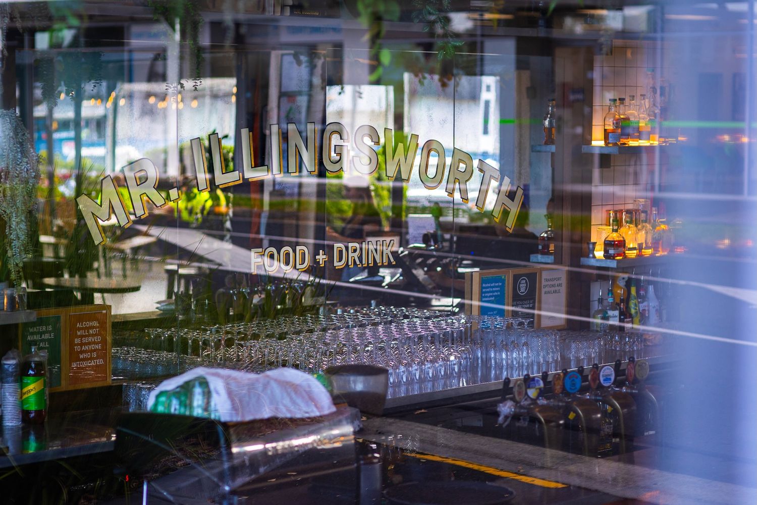 Modern restaurant interior with glass windows, bar seating, and ambient lighting creates an inviting dining atmosphere.