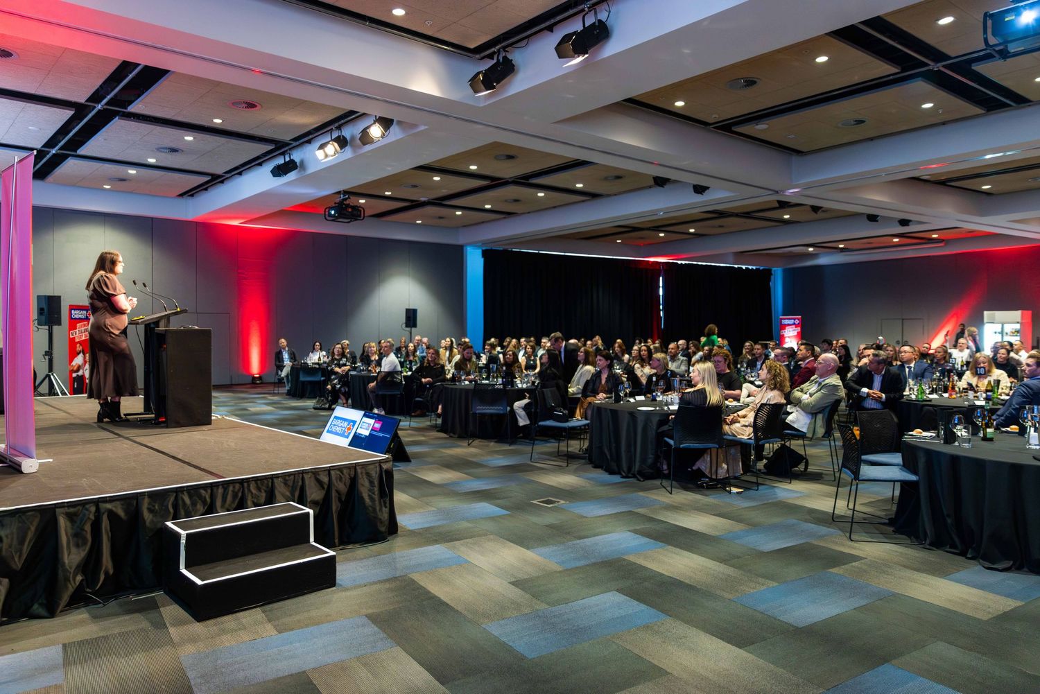 Wide view of a corporate event space with modern lighting and decor.