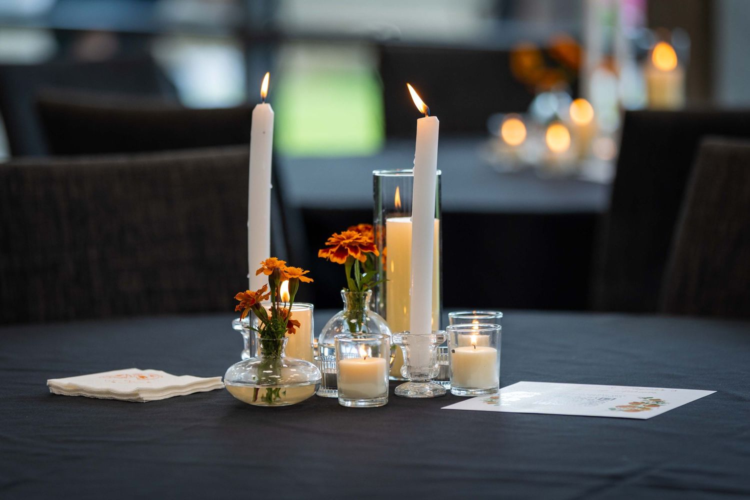 Elegant table setting with lit candles and glassware in a dark restaurant setting.