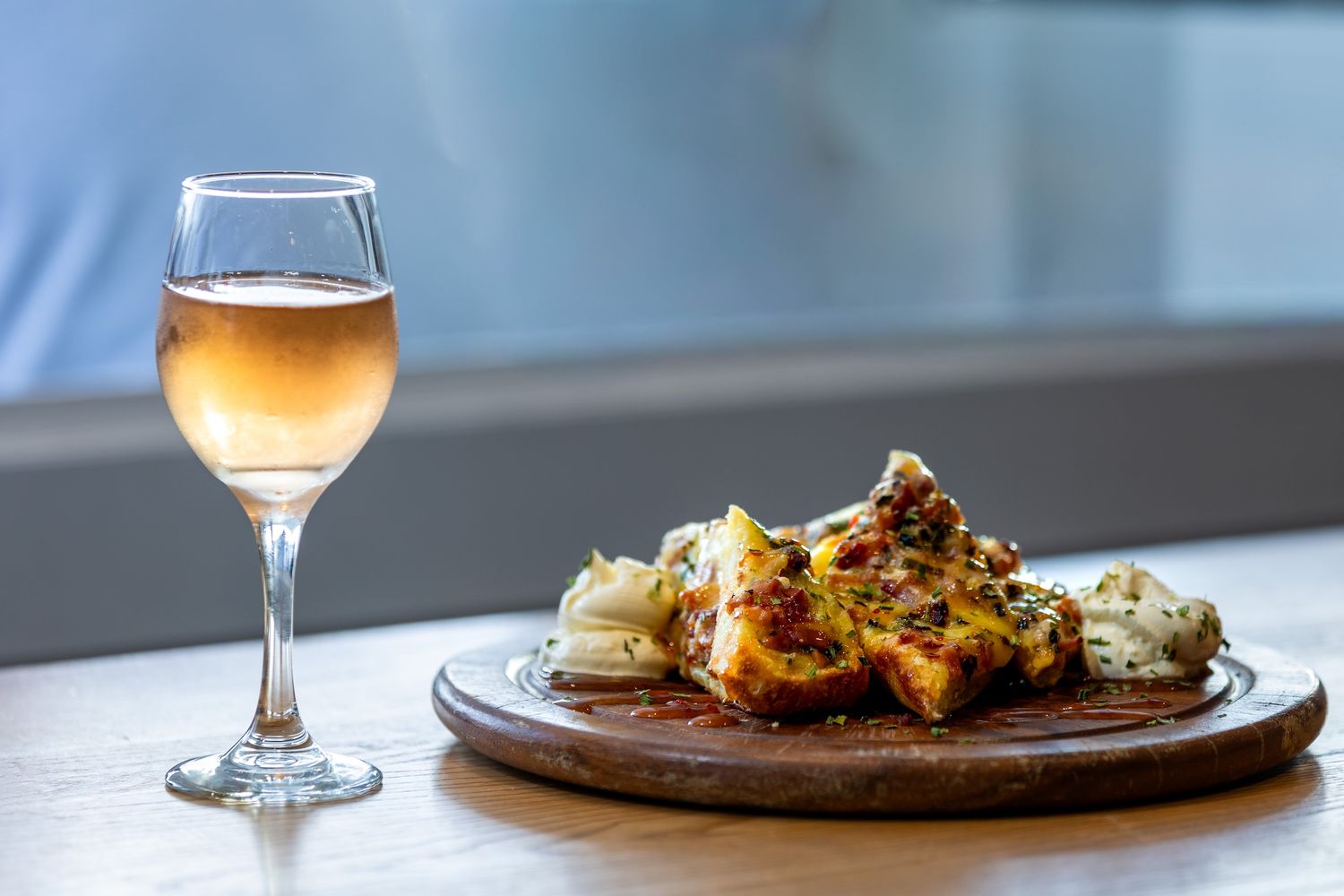 A rustic wooden table set with wine glasses and artfully plated dishes in warm lighting.
