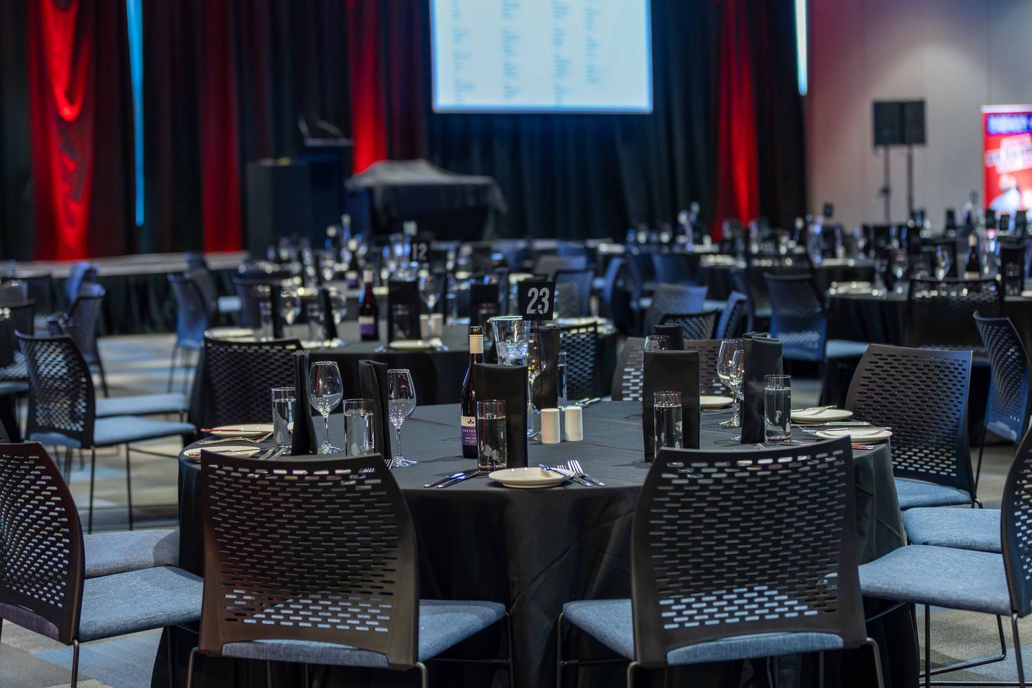 Empty conference room setup with round tables and chairs under dramatic lighting.