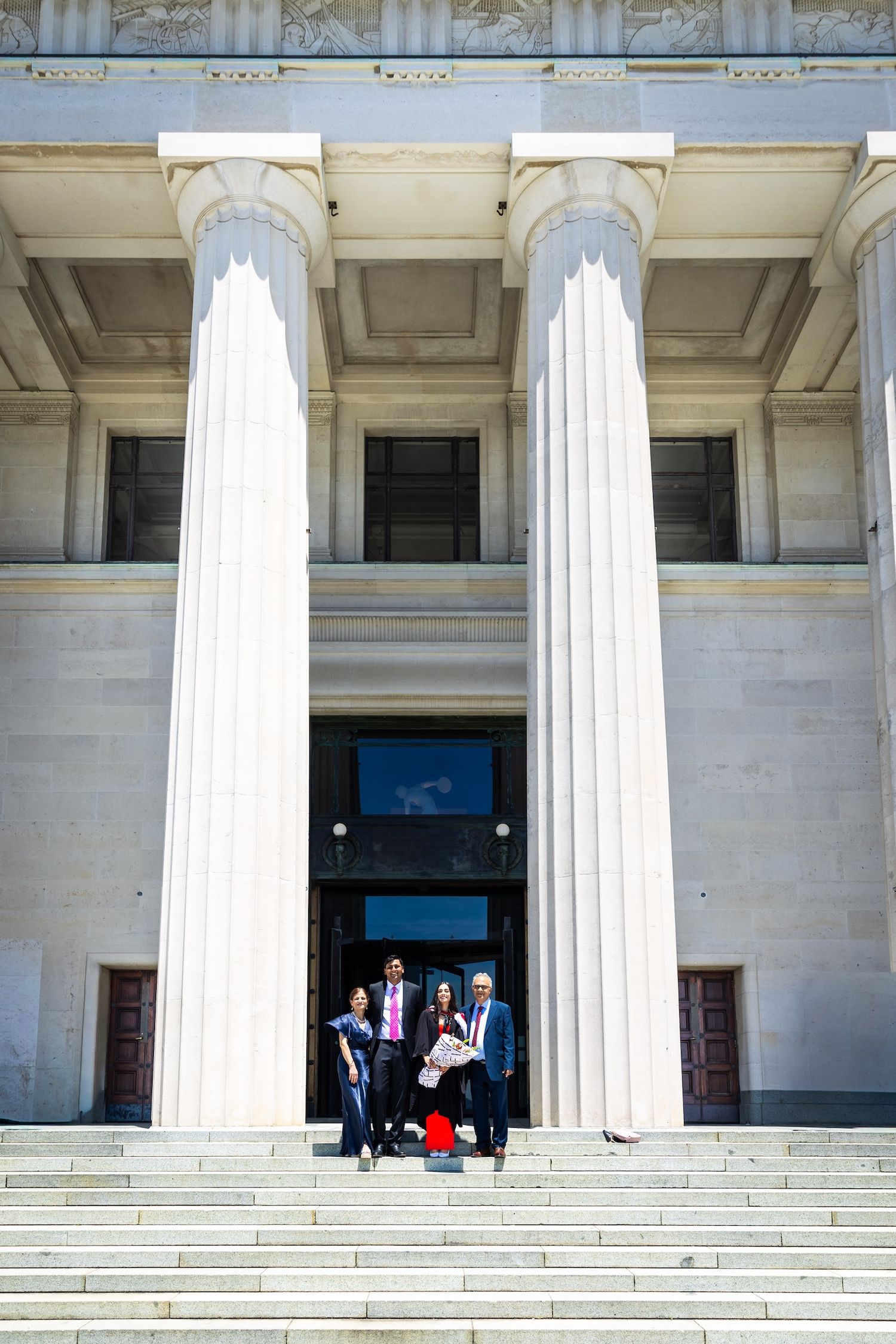 Group of professionals posing on steps of a neoclassical building with large white columns.