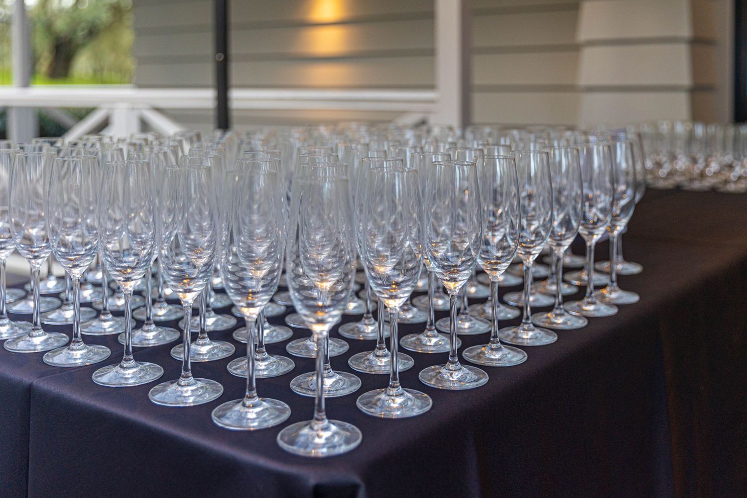 Rows of elegant empty champagne flutes arranged on a dark tablecloth for a formal event or celebration.