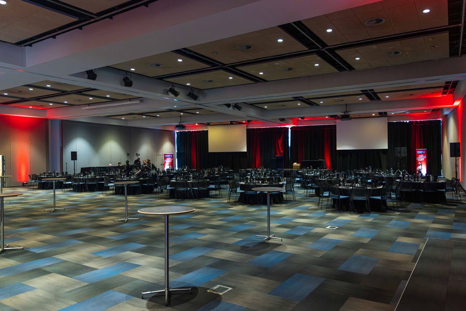 Panoramic view of an empty conference hall with geometric patterned flooring and mood lighting.