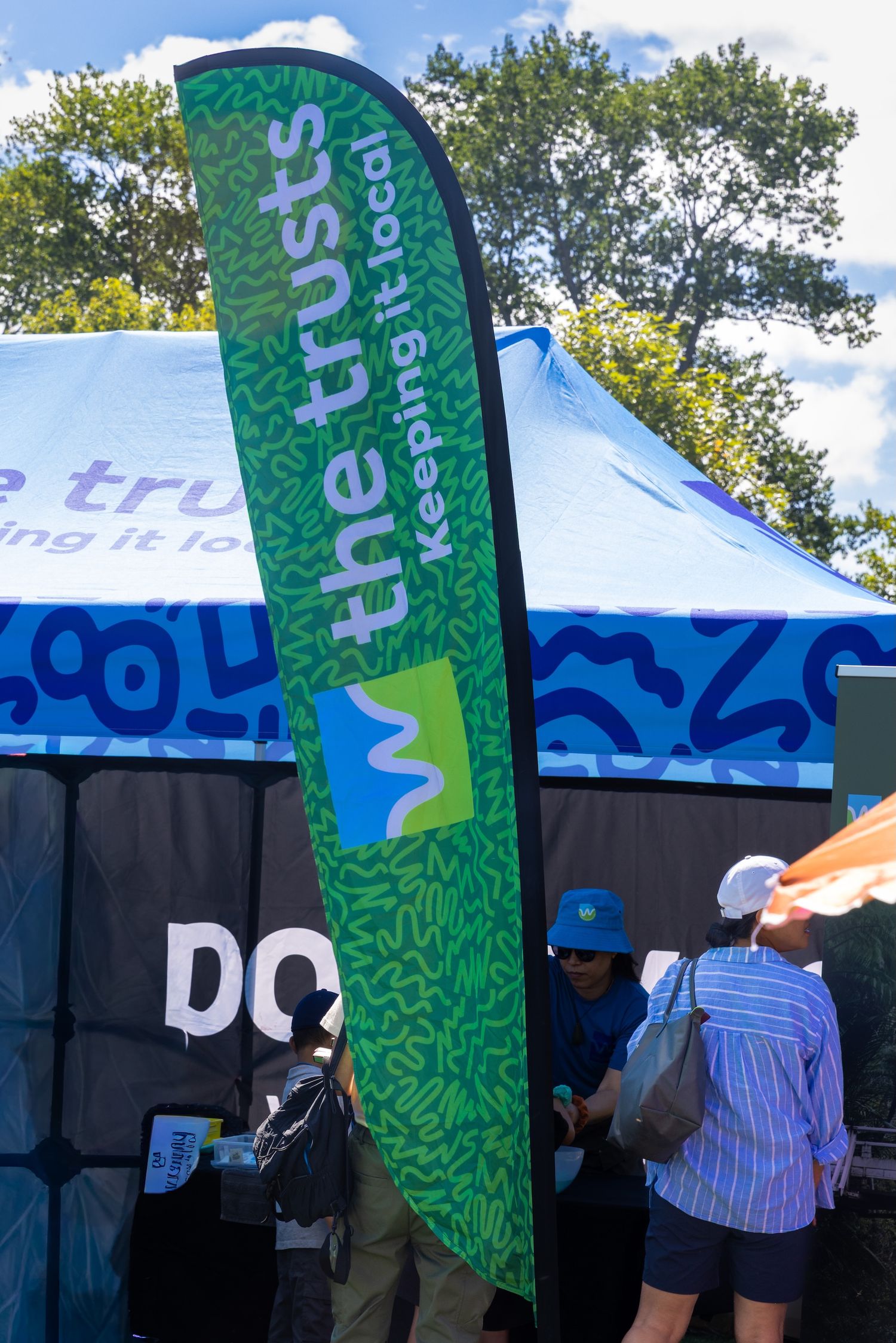 Green feather flags with 'The Trusts' branding line outdoor event space.